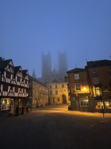 Image shows the spires of Lincoln cathedral in a misty dawn. 